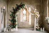 Fond photo Nef oubliée de la collection Arches Noël 2026 - pierre beige, houx, branches blanches - séance famille Noël cérémonielle